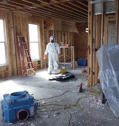 Technician in protective gear in a gutted room during Aurora water cleanup